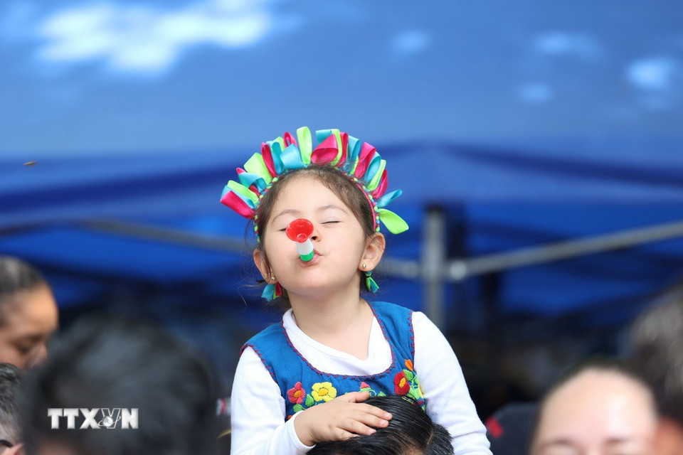 Bé gái Mexico thổi kèn chào đón đoàn diễu hành. (Ảnh: Phi Hùng/TTXVN)