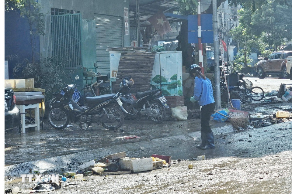 Công nhân Công ty vệ sinh môi trường đô thị dọn vệ sinh khu vực ngã ba Bắc Nam, phường Phan Đình Phùng, ngay khi nước rút. (Ảnh: Hoàng Nguyên/TTXVN)