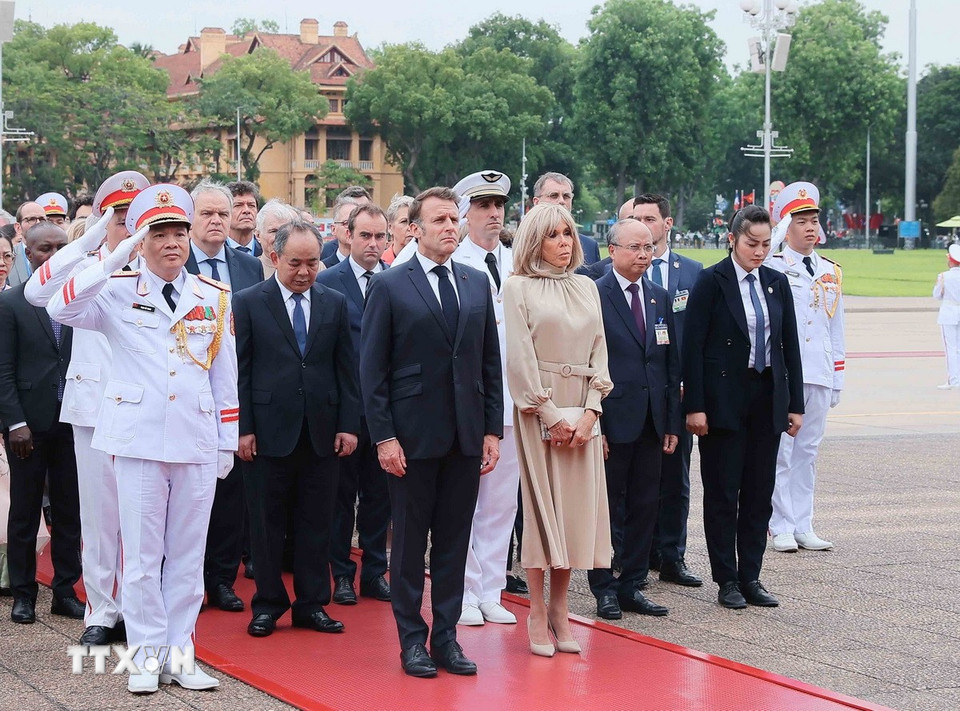 Tổng thống Pháp Emmanuel Macron và Phu nhân cùng các đại biểu kính cẩn tưởng niệm Chủ tịch Hồ Chí Minh. (Ảnh: An Đăng/TTXVN)