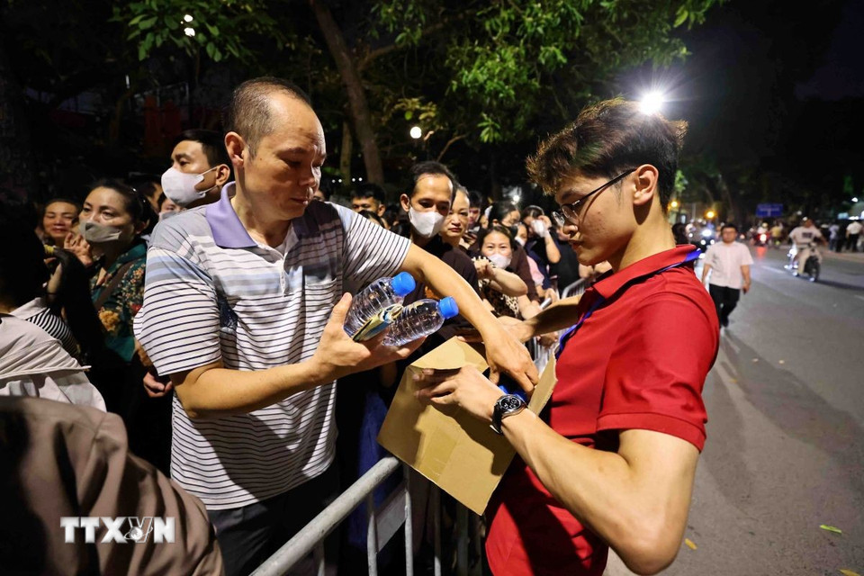 Phật tử các chùa hỗ trợ nước cho người dân xếp hàng trên phố Quán Sứ, để được chiêm bái xá lợi Đức Phật. (Ảnh: Minh Đức/TTXVN)