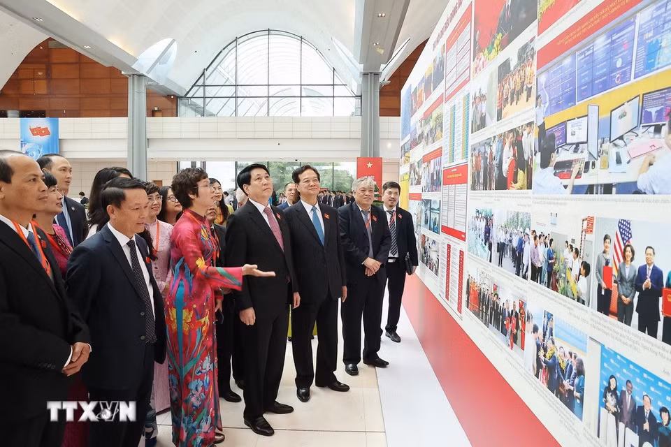 Bí thư Đảng ủy, Tổng Giám đốc TTXVN Vũ Việt Trang giới thiệu với Chủ tịch nước Lương Cường, nguyên Thủ tướng Nguyễn Tấn Dũng và các đại biểu tham quan triển lãm ảnh về Đại hội. (Ảnh: TTXVN)