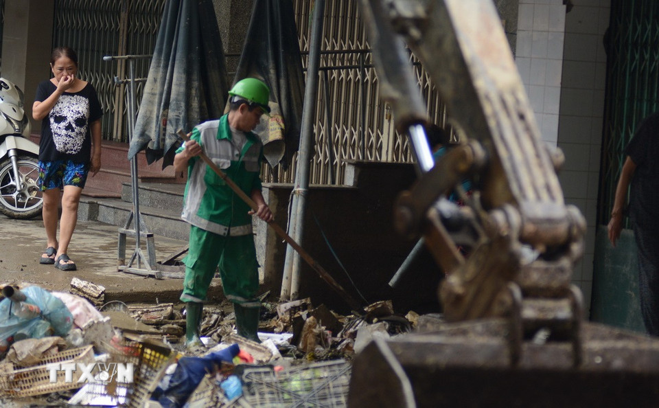 Anh Hoàng Toàn, công nhân của Công ty cổ phần Môi trường và Công trình đô thị Huế, gồng mình dọn những đống rác lớn, bốc mùi tại con ngõ nhỏ gần bên chợ Xép (phường Phú Xuân, thành phố Huế). (Ảnh: Văn Dũng/TTXVN)