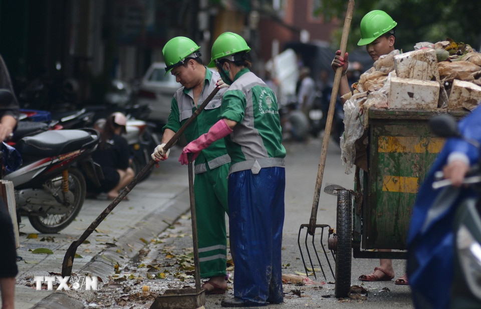 Để sớm trả lại không gian xanh, sạch đẹp, các công nhân môi trường được huy động 100% nhân lực, không quản ngày đêm, mệt nhọc, gồng mình dọn rác. (Ảnh: Văn Dũng/TTXVN)