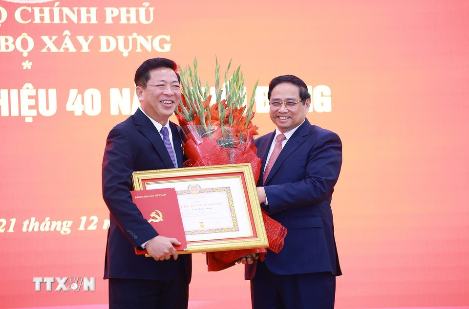 Thủ tướng Phạm Minh Chính trao Huy hiệu 40 năm tuổi Đảng cho Bộ trưởng Bộ Xây dựng Trần Hồng Minh. (Ảnh: Dương Giang/TTXVN)