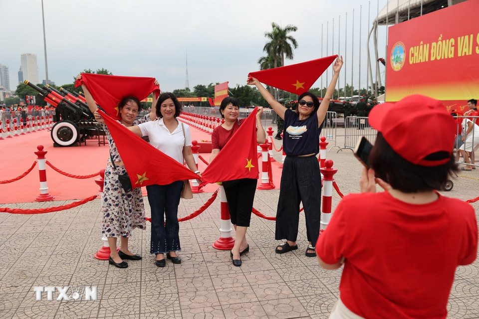 Một gia đình tạo dáng cùng cờ Tổ quốc để chụp ảnh lưu niệm cùng dàn pháo. (Ảnh: Vũ Quang/TTXVN)