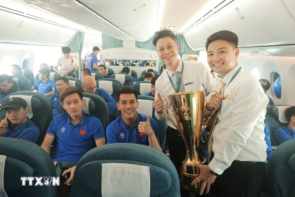 Thành viên tổ bay hân hoan được cầm cúp vô địch ASEAN Cup khi máy bay vừa hạ cánh. (Ảnh: Minh Quyết/TTXVN)