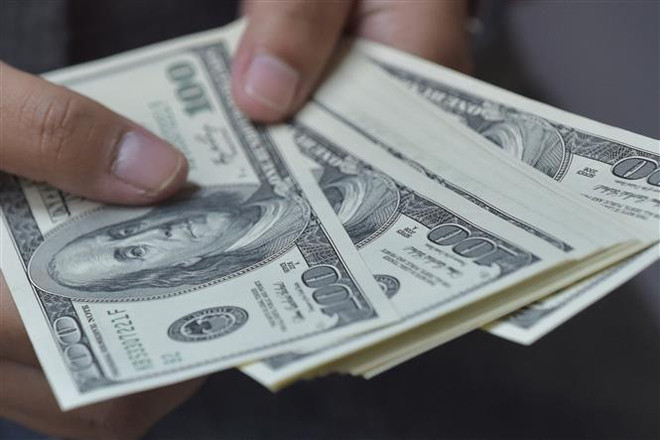 Đồng tiền mệnh giá 100 USD. (Ảnh: AFP/TTXVN) Chuyên gia cảnh báo gánh nặng nợ công tăng vọt trong 15 năm qua ảnh 1
