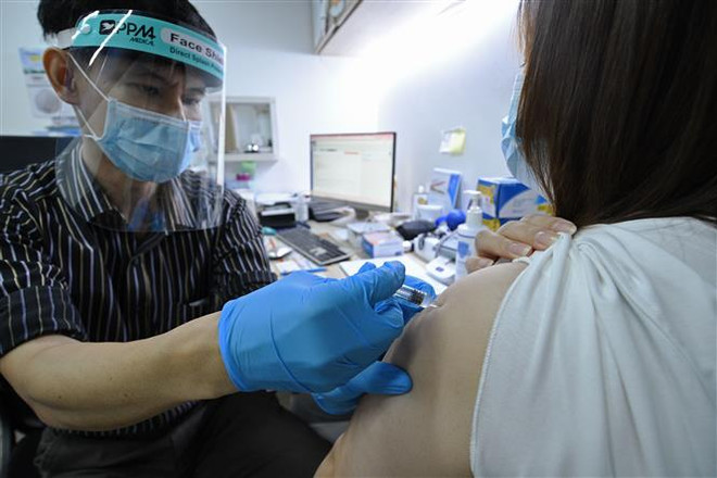Nhân viên y tế tiêm vaccine ngừa COVID-19 cho người dân tại Singapore. (Ảnh: THX/TTXVN) Singapore xem xét nới lỏng hạn chế đối với người tiêm vaccine đầy đủ ảnh 1