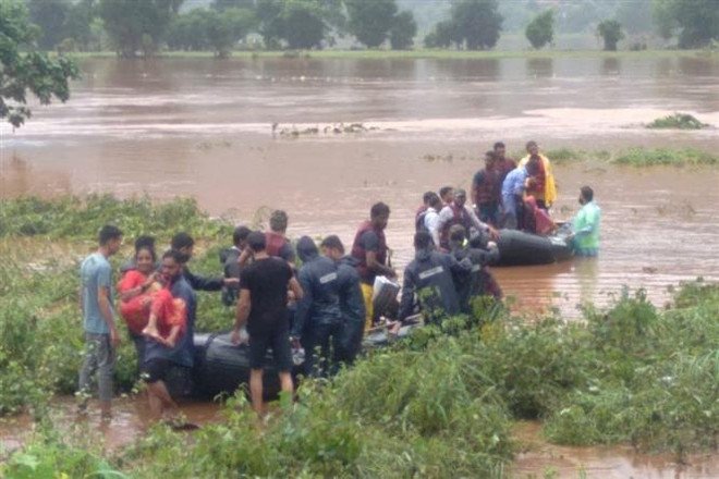 Lực lượng cứu hộ hỗ trợ người dân sơ tán khỏi vùng ngập lụt tại Chiplun, bang Maharashtra, Ấn Độ. (Ảnh: AFP/TTXVN) Gần 70 người thiệt mạng do mưa lũ và sạt lở đất tại Ấn Độ ảnh 1