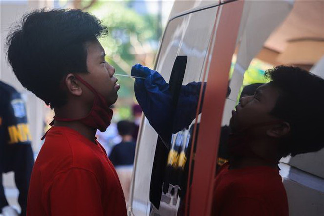 Nhân viên y tế lấy mẫu dịch xét nghiệm COVID-19 cho trẻ em tại Surabaya, Đông Java, Indonesia, ngày 29/6/2020. (Ảnh: THX/TTXVN) Đa số người mắc bệnh COVID-19 tại Indonesia không có triệu chứng ảnh 1