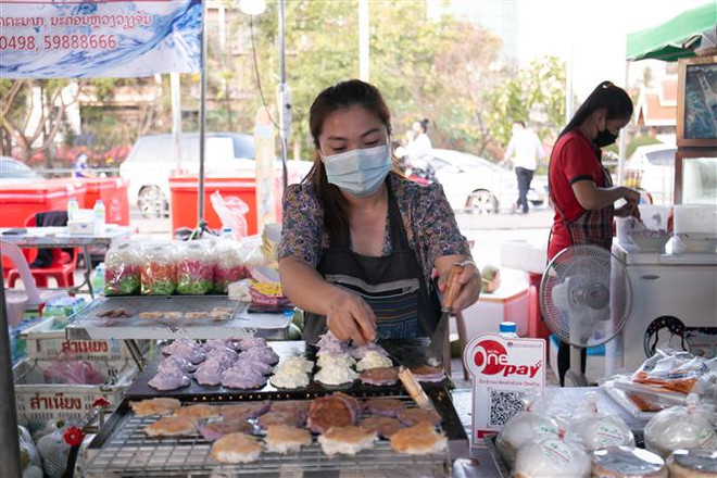 Người dân đeo khẩu trang phòng dịch COVID-19 tại hội chợ ẩm thực ở Vientiane, Lào. (Ảnh: THX/TTXVN) Lào nghi nhận ca lây nhiễm biến thể Omicron đầu tiên trong cộng đồng ảnh 1