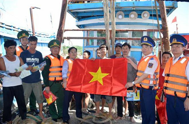Thiếu tướng Bùi Quốc Oai tặng cờ Tổ quốc cho ngư dân tại âu cảng Bạch Long Vĩ. (Ảnh: TTXVN) Cảnh sát biển đồng hành cùng ngư dân huyện đảo Bạch Long Vĩ ảnh 3