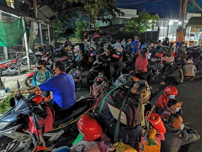 Người dân tập trung tại chốt kiểm soát dịch COVID-19 của tỉnh Hậu Giang trên Quốc lộ 1A tối 25/9 để chờ Cảnh sát giao thông dẫn đường đi qua địa bàn Hậu Giang. (Ảnh: Thanh Liêm/TTXVN) Giải quyết tình trạng người dân chạy xe máy về quê bị kẹt ở Hậu Giang ảnh 1