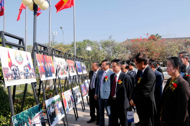 Ông Nguyễn Đức Lợi cùng các quan khách đang đi thăm quan Triển lãm ảnh. (Ảnh: Phạm Kiên/Vietnam+) TTXVN và KPL trưng bày ảnh tư liệu quý về mối quan hệ Việt Nam-Lào ảnh 5