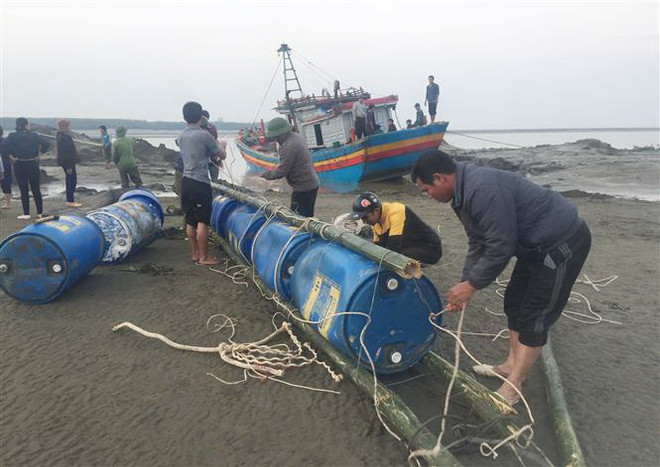 Các ngư dân nỗ lực dùng nhiều phương án trục vớt tàu cá. (Ảnh: Nguyễn Oanh/TTXVN) Nghệ An trục vớt thành công tàu cá mắc cạn tại cửa Lạch Vạn ảnh 1