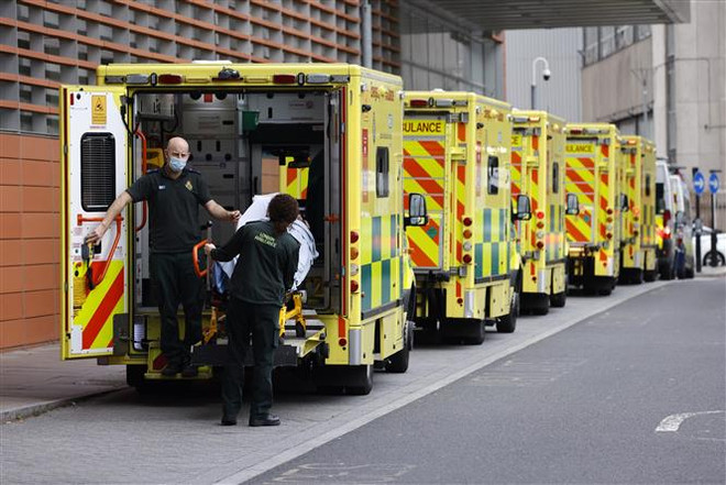 Nhân viên y tế chuyển bệnh nhân COVID-19 tới bệnh viện ở London, Anh. (Ảnh: AFP/TTXVN) Chuyên gia Anh lo ngại về việc rút ngắn cách ly với người mắc COVID-19 ảnh 1