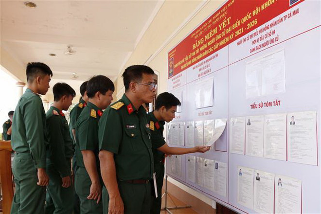 Các chiến sỹ thuộc Bộ Chỉ huy Quân sự tỉnh Cà Mau theo dõi danh sách cử tri được niêm yết tại đơn vị. (Ảnh: Kim Há/TTXVN) Khẳng định vai trò xuyên suốt của Mặt trận Tổ quốc trong bầu cử ảnh 3