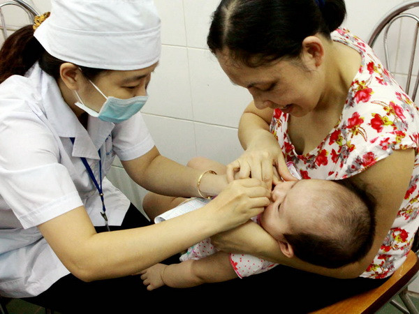 Nhân viên y tế phường Đống Mác, quận Hai Bà Trưng kiểm tra thông tin sức khỏe trước khi cho trẻ uống vitamin A. (Ảnh: Dương Ngọc/TTXVN) Khoảng 5 triệu trẻ em sẽ được uống bổ sung vitamin A ảnh 1