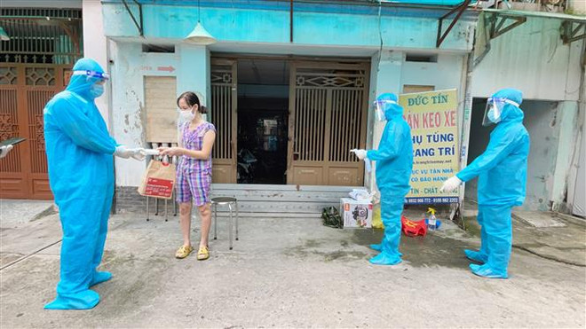 Nhân viên y tế trạm y tế lưu động phường 25, quận Bình Thạnh phát túi thuốc cho F0 điều trị tại nhà. (Ảnh: Đinh Hằng/TTXVN) TP. HCM xây dựng chính sách động viên, giữ chân lực lượng y tế cơ sở ảnh 1