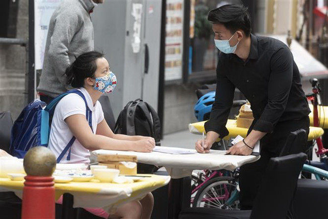Người dân đeo khẩu trang tại một nhà hàng. (Ảnh: AFP/TTXVN) EU đánh giá nguy cơ lây nhiễm virus SARS-CoV-2 trong không khí ảnh 2