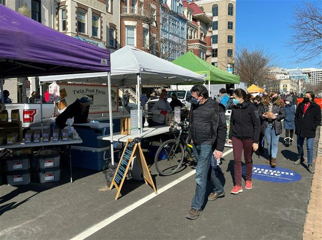 Người dân đeo khẩu trang phòng lây nhiễm COVID-19 tại một khu chợ ở Washington, DC, Mỹ, ngày 21/2/2021. (Ảnh: AFP/TTXVN) Mỹ treo cờ rủ tưởng niệm 500.000 người tử vong vì dịch COVID-19 ảnh 1