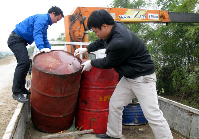 Thu gom các thùng phuy chất lỏng bị đổ trộm xuống bờ đê sông Đáy. (Ảnh: Văn Đạt/TTXVN) Điều tra vụ đổ trộm 11 thùng phuy chất lỏng có mùi dầu nhớt thải ảnh 1