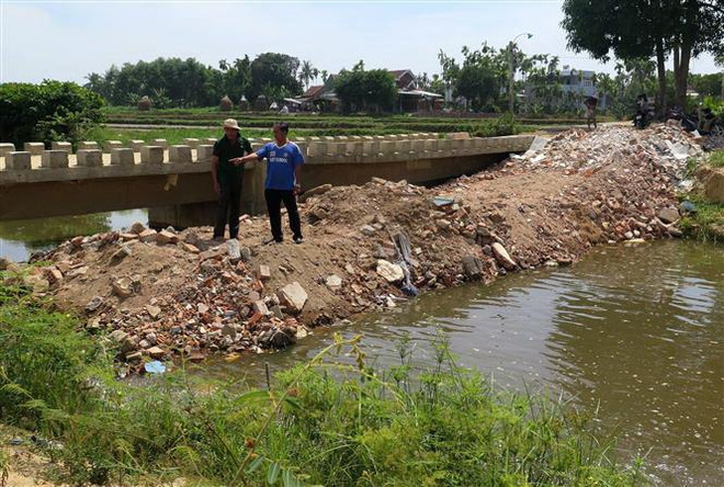 Người dân đổ đất lấp ngang đoạn kênh qua địa bàn thôn Điền Chánh Trung. (Ảnh: Phước Ngọc/TTXVN) Quảng Ngãi: Dân đổ đất lấp kênh phản đối khu công nghiệp xả thải ảnh 1
