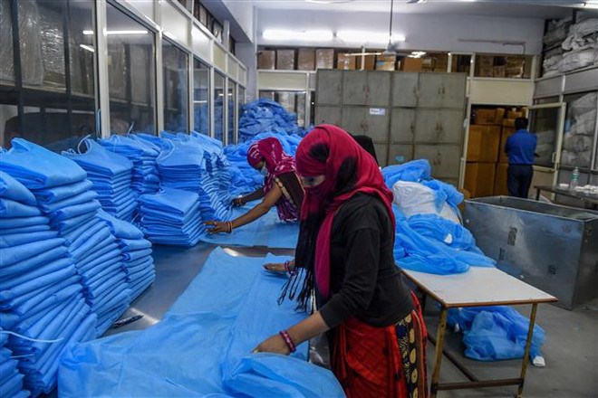 Công nhân làm việc tại cơ sở sản xuất đồ bảo hộ Nikshe ở Ahmedabad, Ấn Độ. (Ảnh: AFP/TTXVN) Hàng triệu công nhân dệt may có nguy cơ mất việc do COVID-19 ảnh 1