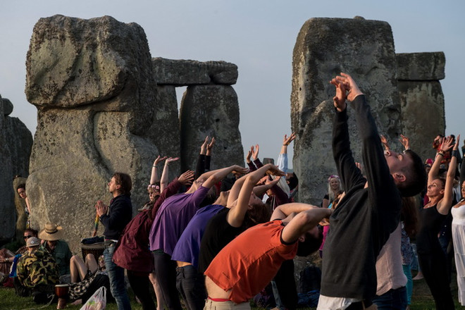 Du khách tập yoga để chào đón khoảnh khắc Mặt Trời mọc của ngày dài nhất trong năm ở Vòng tròn đá Stonehenge ngày 21/6. (Nguồn: AFP/TTXVN) Người Anh đón ngày dài nhất trong năm tại vòng tròn đá Stonehenge ảnh 3