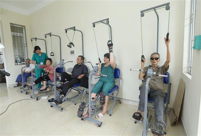 Cán bộ Cơ sở Bảo trợ Xã hội Tổng hợp tỉnh Lạng Sơn hướng dẫn các đối tượng tập phục hồi chức năng tại Cơ sở. (Ảnh: Anh Tuấn/TTXVN) Đề xuất nâng mức chuẩn trợ giúp xã hội lên 500.000 đồng mỗi tháng ảnh 1