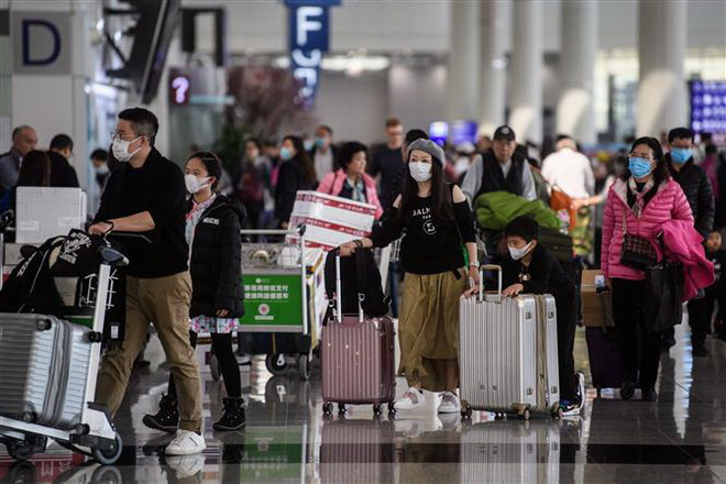 Hành khách đeo khẩu trang để phòng tránh lây nhiễm virus corona tại sân bay quốc tế Hong Kong, Trung Quốc, ngày 22/1/2020. (Ảnh: AFP/TTXVN) Bệnh viêm phổi lạ: Singapore, Đài Loan hủy các chuyến bay tới Vũ Hán ảnh 1