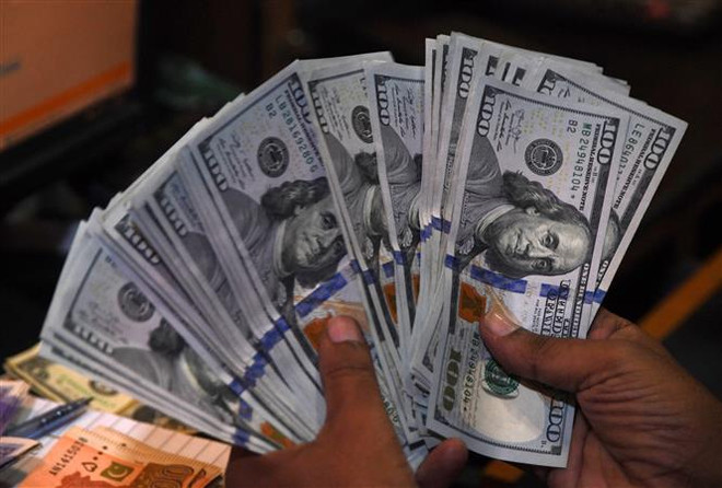 Kiểm đồng USD tại một quầy giao dịch tiền tệ. (Ảnh: AFP/TTXVN) Mỹ ghi nhận mức thâm hụt ngân sách cao thứ 2 trong lịch sử ảnh 1