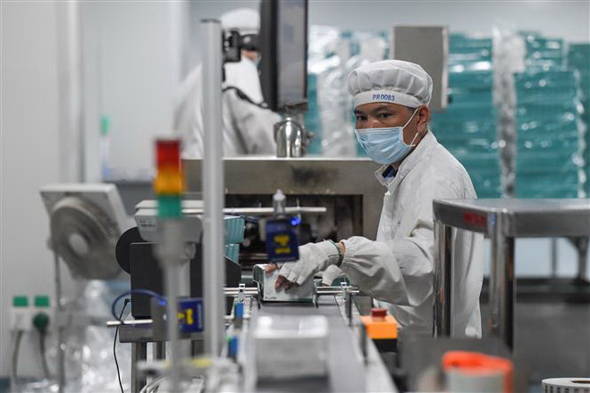 Công nhân làm việc tăng ca để sản xuất thuốc tại Công ty dược ở Hải Khẩu, tỉnh Hải Nam, Trung Quốc trong bối cảnh dịch viêm đường hô hấp cấp do virus corona chủng mới bùng phát. (Ảnh: THX/TTXVN) Thế khó của doanh nghiệp Trung Quốc trong cơn cuồng phong corona ảnh 1