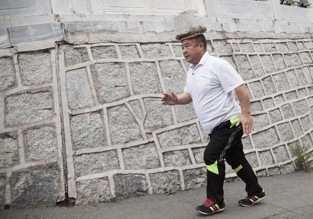 Ông Cong Yan đi bộ trên đường phố với một khối ximăng trên đầu. (Nguồn: shanghaiist.com) Đội ximăng tập thể dục, người đàn ông Trung Quốc giảm 30kg ảnh 1