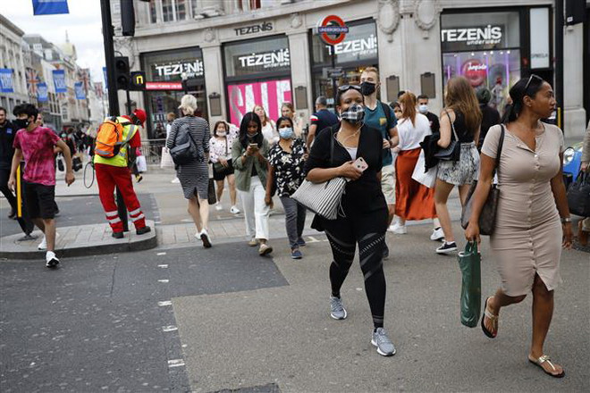 Người dân đeo khẩu trang phòng lây nhiễm COVID-19 khi di chuyển trên đường phố tại London, Anh. (Ảnh: AFP/TTXVN) IMF dự báo nền kinh tế Anh sẽ phục hồi yếu hơn dự kiến ảnh 1
