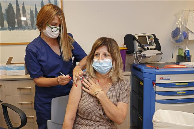 Nhân viên y tế tiêm vaccine Pfizer/BioNTech ngừa COVID-19 cho người dân tại Tel Aviv, Israel. (Ảnh: AFP/TTXVN) Israel chuẩn bị tiêm mũi 3 vaccine của Pfizer cho người lớn tuổi ảnh 1