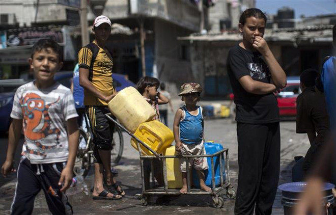 Người dân Palestine xếp hàng lấy nước sinh hoạt tại một trại tị nạn ở Dải Gaza. (Ảnh: AFP/TTXVN) Palestine hối thúc các nước Arab thực hiện cam kết viện trợ tài chính ảnh 1
