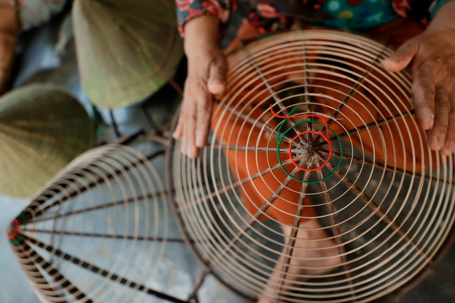 Người thợ chằm nón Làng nón Đốc Sơ (phường Hương Sơ, thành phố Huế) chuẩn bị nan tre được vót nhỏ uốn quanh khung hình chóp trước khi chằm nón. (Ảnh: Minh Quyết/TTXVN) ttxvn-non la sen (10).jpg