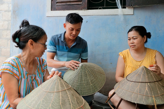 Anh Nguyễn Thanh Thảo trao đổi với những người thợ làng nón truyền thống Đốc Sơ (Huế) về sản phẩm nón sen. (Ảnh: Minh Quyết/TTXVN) ttxvn-non la sen (12).jpg