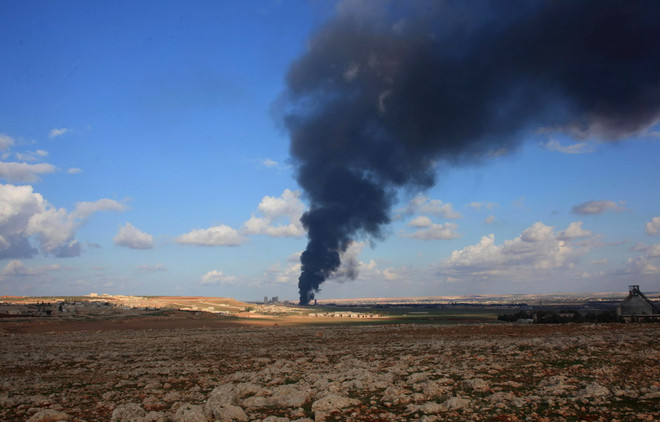 Khói bốc lên từ một kho vũ khí của lực lượng nổi dậy sau khi quân đội Syria giành lại quyền kiểm soát nông trại Al-Maleh, phía tây khu vực đồi Handarat ngày 15/12. (Ảnh: AFP/TTXVN) Các nước Trung Đông và Bắc Phi vẫn chìm trong chảo lửa ảnh 1