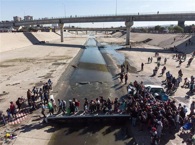 Người di cư Trung Mỹ vượt đoạn sông Tijuana để tới cửa khẩu El Chaparral, gần biên giới Mỹ-Mexico. (Ảnh: AFP/TTXVN) Người di cư trái phép tập trung tại cửa khẩu Mỹ-Mexico tăng kỷ lục ảnh 1