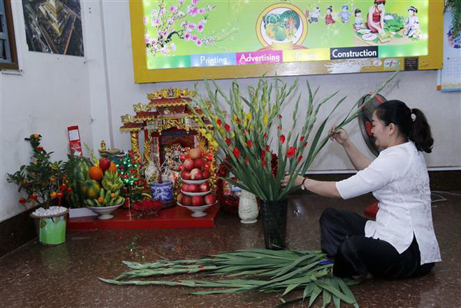 Chị Hương (vợ anh Nam) cắm một lọ hoa dơn - loại hoa người Việt hay dùng trang trí nhà cửa mỗi dịp đón Tết. (Ảnh: Phạm Kiên/TTXVN) Người Việt tại Lào giúp nhau vượt qua nỗi nhớ quê hương dịp Tết đến ảnh 2