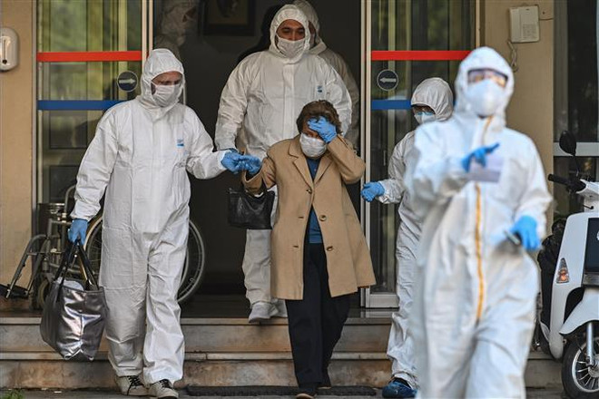 Nhân viên y tế hỗ trợ một bệnh nhân nghi nhiễm COVID-19. (Ảnh minh họa. AFP/TTXVN) Cảnh báo trường hợp người Việt nghi nhiễm COVID-19 ở Belarus ảnh 1
