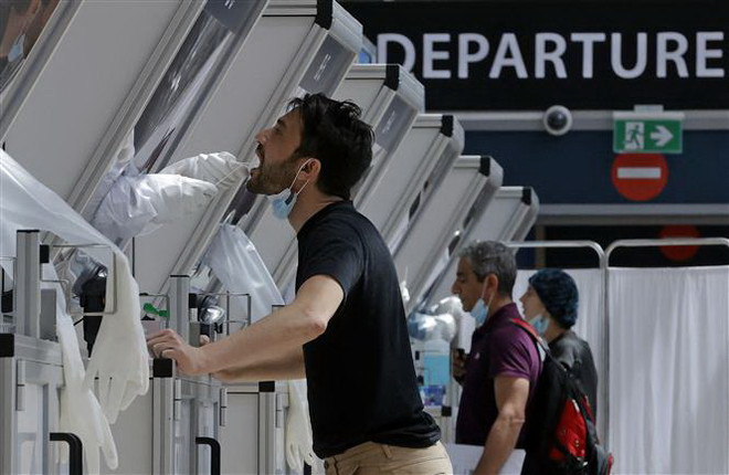 Nhân viên y tế lấy mẫu xét nghiệm COVID-19 cho hành khách tại sân bay. (Ảnh minh họa. AFP/TTXVN) EU hướng tới sử dụng "hộ chiếu vaccine" để mở cửa du lịch Hè 2021 ảnh 1