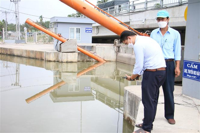 Cán bộ, nhân viên Công ty THHH Một thành viên Khai thác công trình thủy lợi Bến Tre kiểm tra độ mặn tại khu vực cống Châu Thới, huyện Giồng Trôm, Bến Tre. (Ảnh: Công Trí/TTXVN) Khẩn trương trữ nước ứng phó với xâm nhập mặn gia tăng ở ĐBSCL ảnh 1