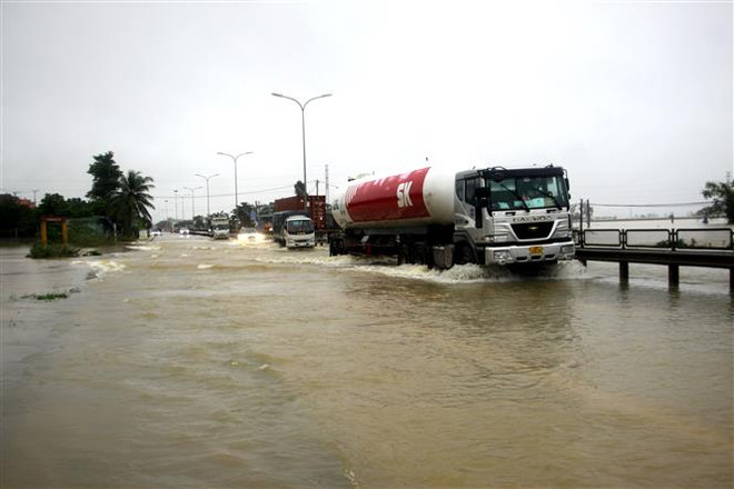 Hàng trăm mét Quốc lộ 1A qua địa bàn xã Tam Đàn, huyện Phú Ninh bị ngập sâu trong nước. (Ảnh: Phước Tuệ/TTXVN) Quảng Nam điều tiết giao thông tại tuyến đường bị chia cắt vì mưa lớn ảnh 1