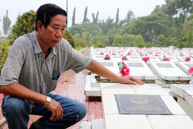 Anh Nguyễn Thanh Hà bên cạnh mộ liệt sỹ chưa tìm được thân nhân tại Nghĩa trang liệt sỹ huyện Cái Bè. (Ảnh: Hữu Chí/TTXVN) ttxvn-tim than nhan3.jpg