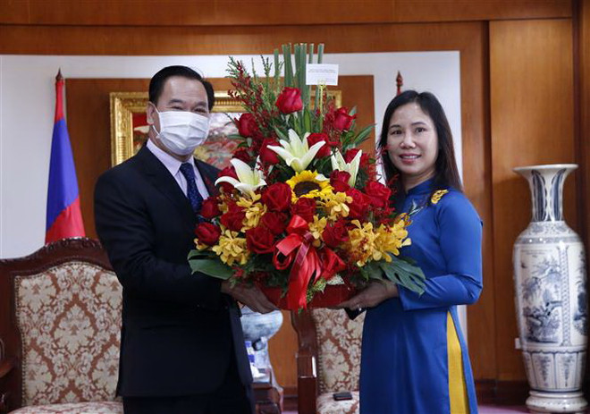 Ông Thongsalith Mangnomek, Bí thư Trung ương Đảng, Chánh Văn phòng Trung ương Đảng Nhân dân cách mạng Lào tặng hoa chúc mừng Đại biện lâm thời Đại sứ quán Việt Nam tại Lào bà Trịnh Thị Tâm. (Ảnh: Phạm Kiên/TTXVN) Lãnh đạo bộ, ngành của Lào chúc mừng ngày thành lập ĐCS Việt Nam ảnh 1