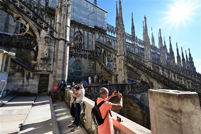Khách du lịch tham quan Nhà Thờ Chính Tòa Milano ở Milan, Italy. (Ảnh: AFP/TTXVN) LHQ kêu gọi tái khởi động ngành du lịch xanh, bảo đảm công bằng ảnh 1