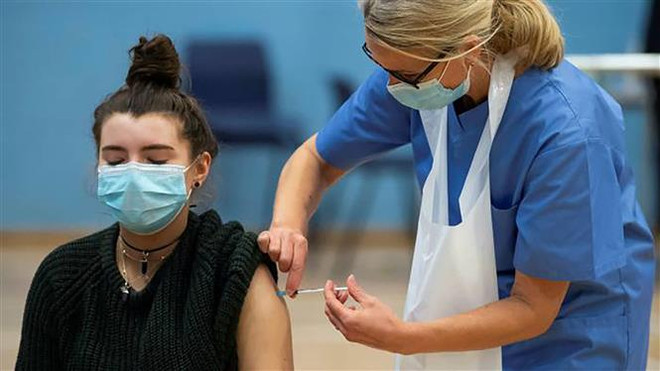 Nhân viên y tế Anh tiêm vaccine ngừa COVID-19 cho người dân tại trung tâm tiêm chủng di động ở phía Bắc London. (Ảnh: AFP/TTXVN) Toàn thế giới ghi nhận gần 231 triệu ca nhiễm virus SARS-CoV-2 ảnh 2